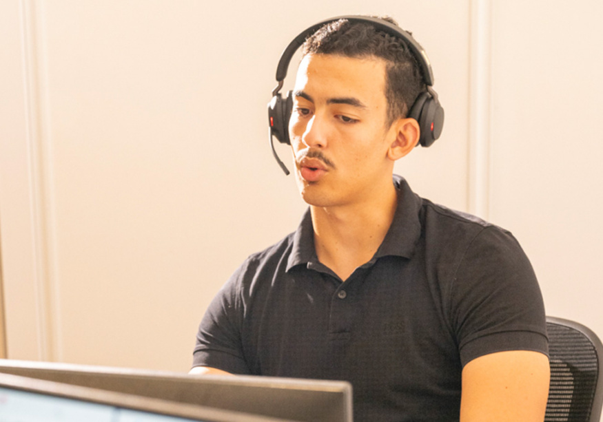 Un collaborateur avec un casque téléphonique travaille devant son ordinateur