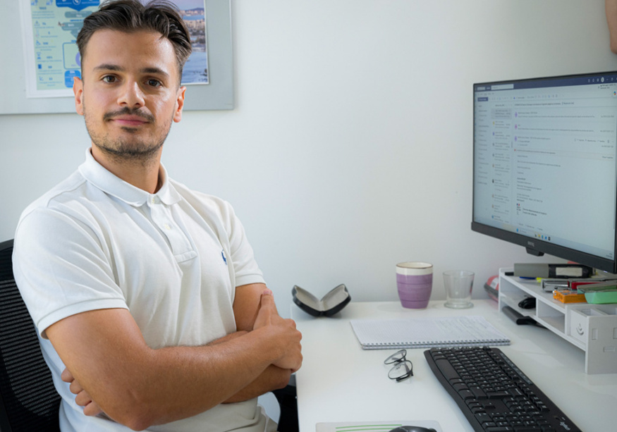 Portrait d'un collaborateur bras croisés devant son bureau informatique